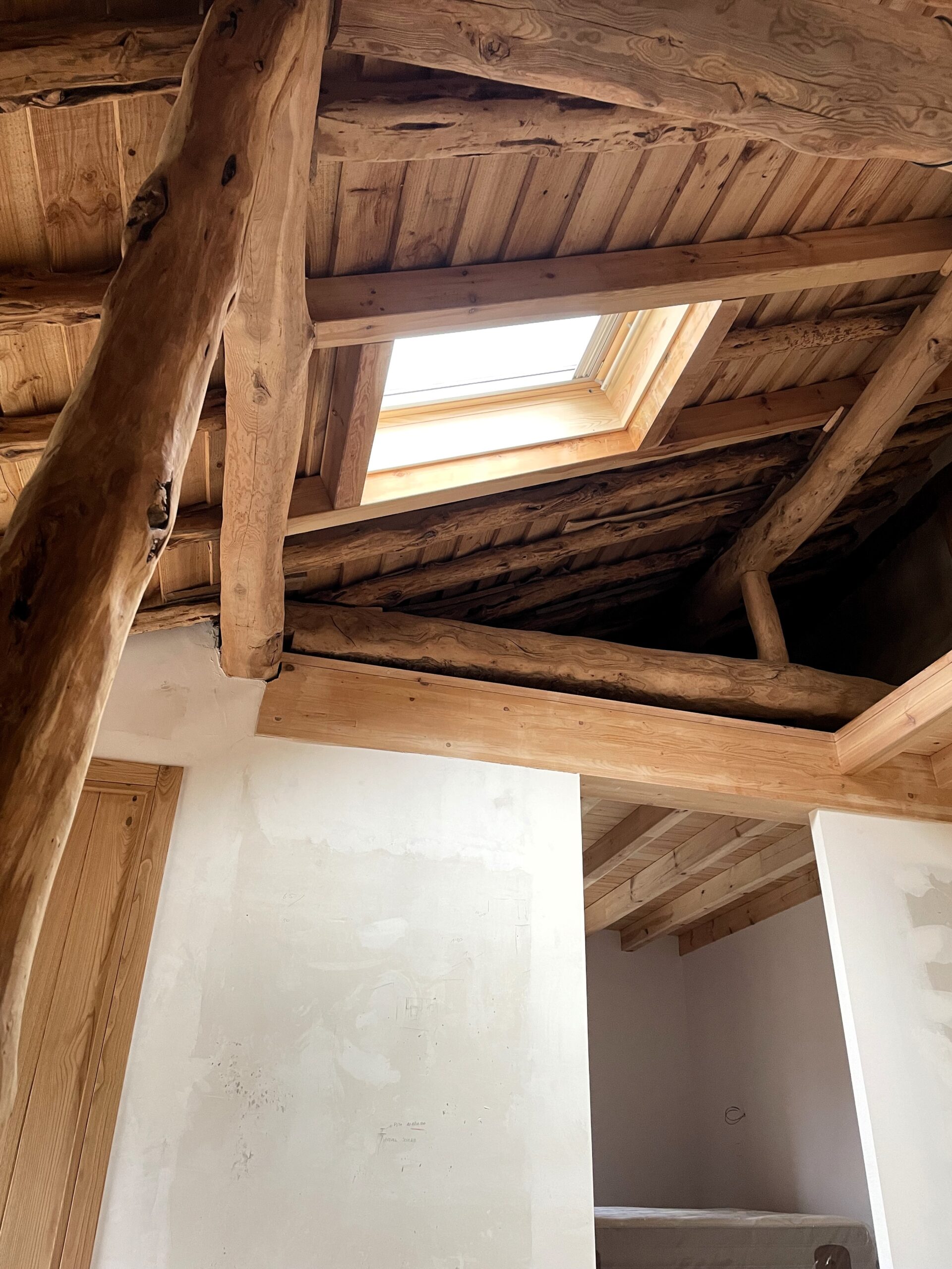 rehabilitacion-segovia-pedraza-ignacio-barco-arquitecto Techo de madera restaurado en vivienda tradicional, con vigas de madera originales y paredes de piedra blanca.